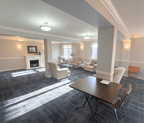A room with a fireplace, chairs, and a table.