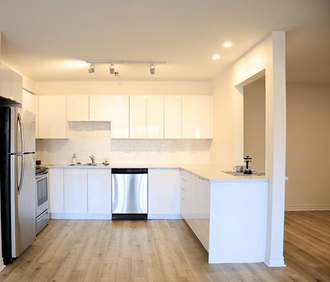 A kitchen with white cabinets and a wooden floor.
