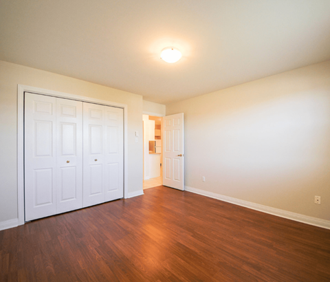 A room with a white door and wooden floors.