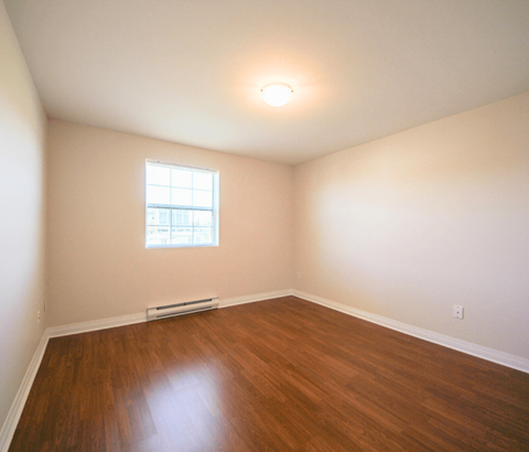 A room with a window and a radiator on the floor.