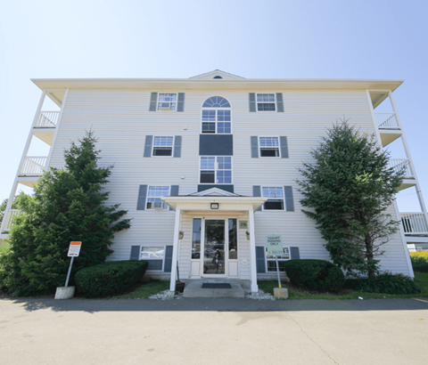 A two-story building with a white facade and a covered entrance.
