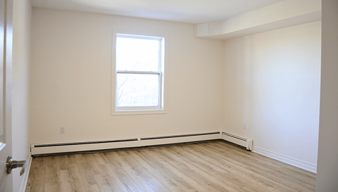 A room with a window and wooden flooring.