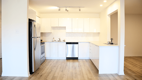 A modern kitchen with white cabinets and a wooden floor.