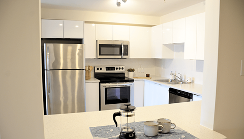 A kitchen with a stainless steel refrigerator, microwave, oven, and dishwasher.