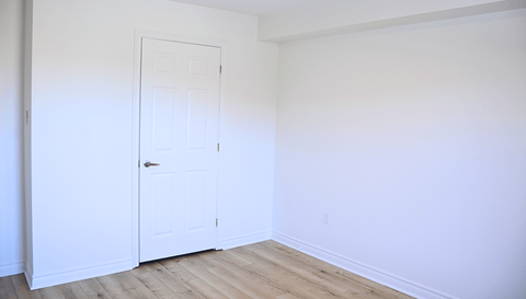 A white door is in a room with a wooden floor.