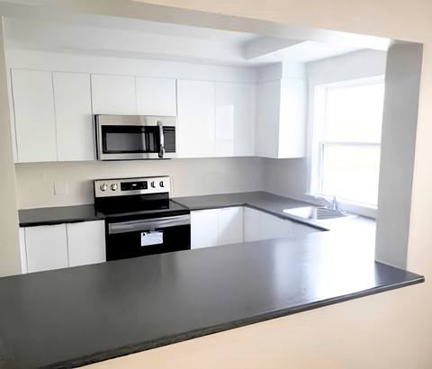 A modern kitchen with a black countertop and white cabinets.