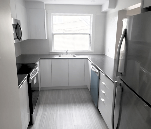 A kitchen with white cabinets and a window.