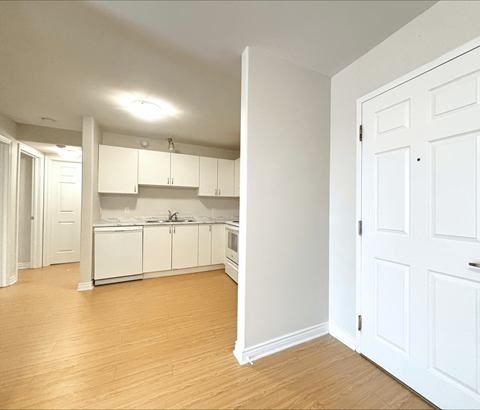A kitchen with white cabinets and a wooden floor.