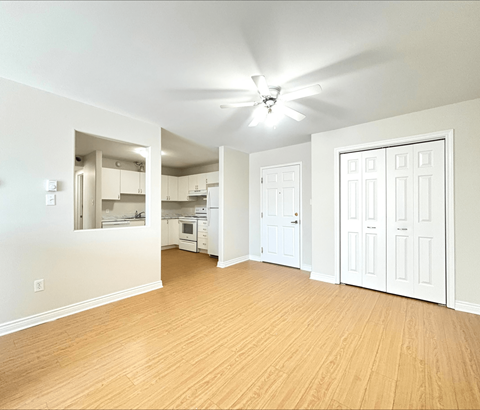 A room with a ceiling fan and wooden flooring.