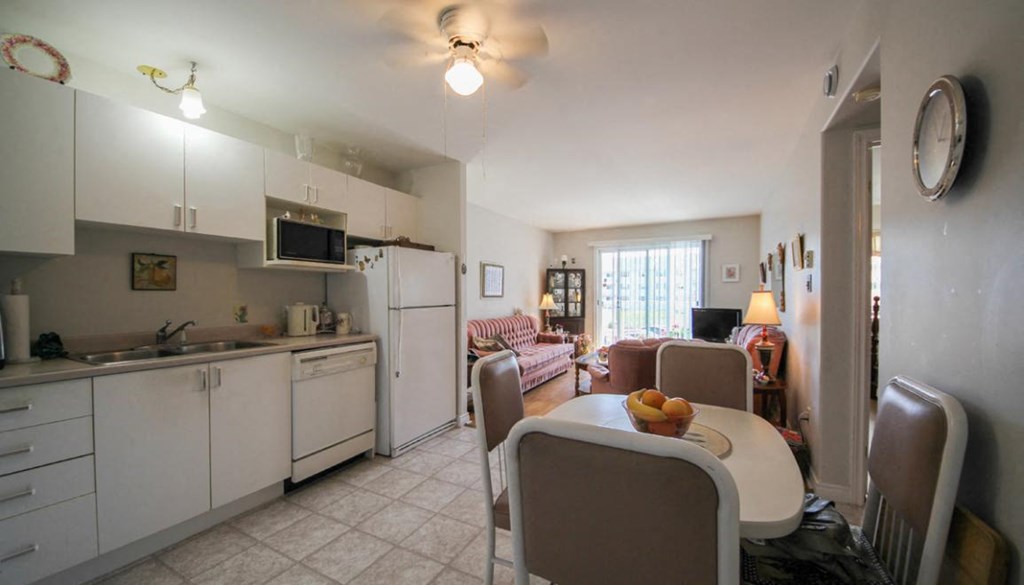 A kitchen with white cabinets and a dining table with chairs.