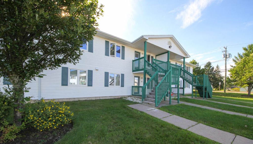 the front of a white house with green stairs