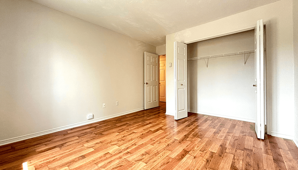an empty living room with wood flooring and an open closet