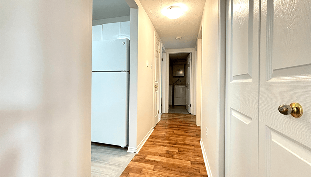 a hallway with a refrigerator and a door to a kitchen