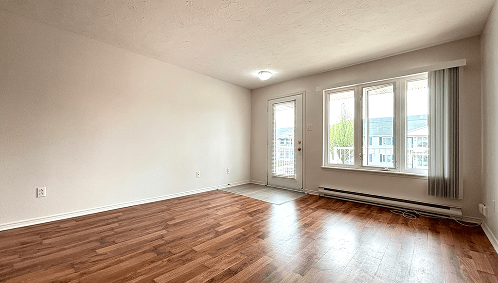 the living room of an empty house with wood floors and a window