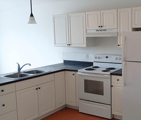 A white kitchen with a black counter top and white appliances.