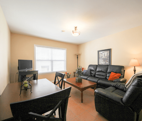 A living room with a black leather couch and a wooden coffee table.