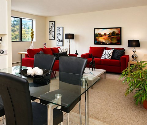 A modern living room with a glass dining table and red couch.