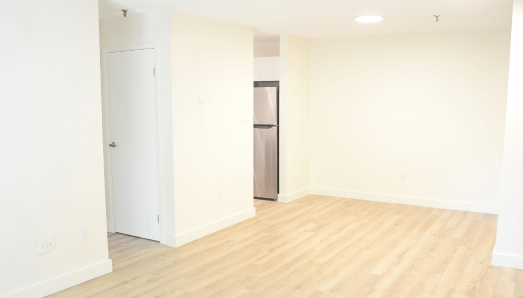 A white door is on the left and a white cabinet is on the right in a room with wooden flooring.
