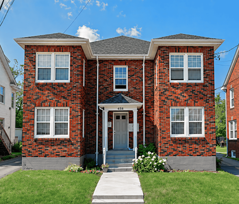 A red brick house with a grey roof and a white door.