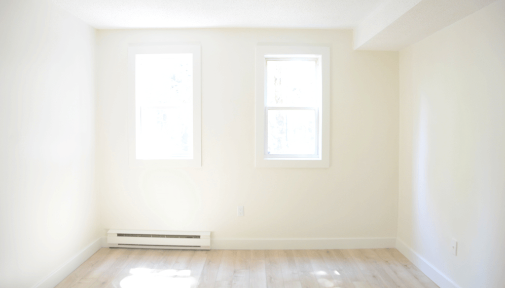 A room with a window and a radiator on the floor.
