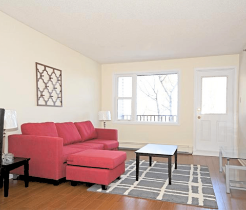 A red couch in a living room with a small table in front of it.