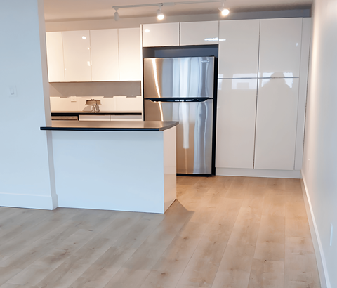 A kitchen with a white counter and a black fridge.