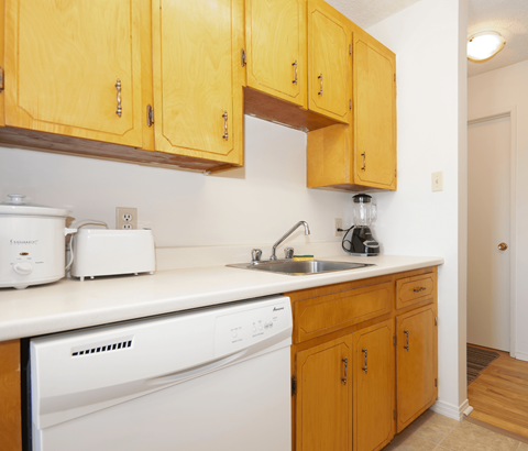 A kitchen with wooden cabinets and a white dishwasher.