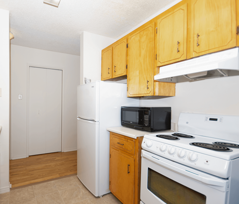 A kitchen with white appliances and wooden cabinets.