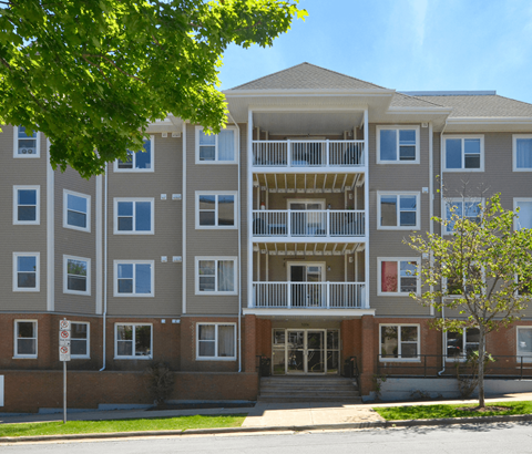 A large apartment building with a tree in front.
