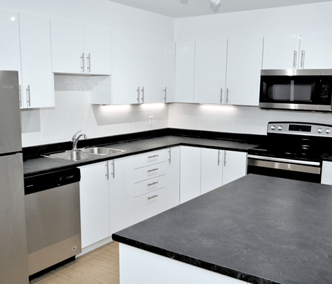 A modern kitchen with white cabinets and black countertops.