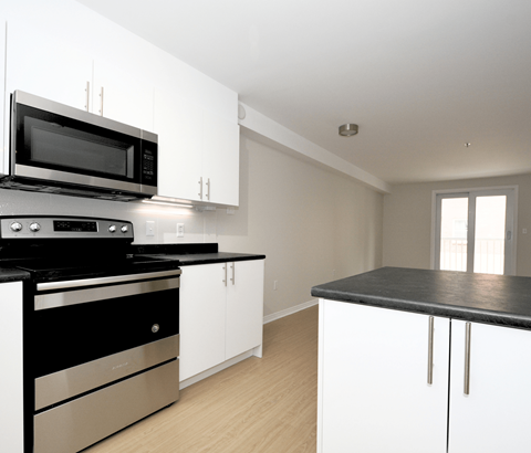 A modern kitchen with black and white appliances and cabinets.