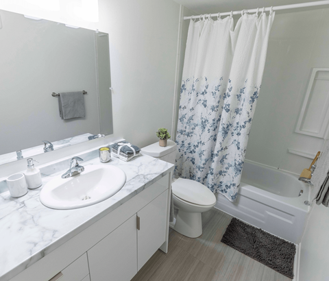 A white bathroom with a sink, toilet, and shower.