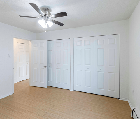 A room with a ceiling fan and white walls.