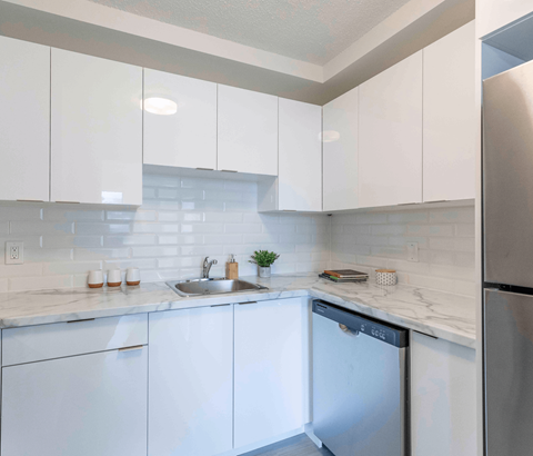 A kitchen with white cabinets and a stainless steel refrigerator.