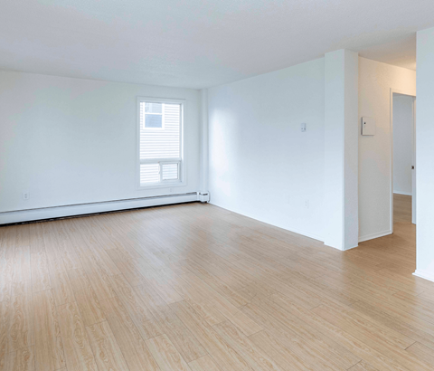 A room with wooden flooring and a window with blinds.