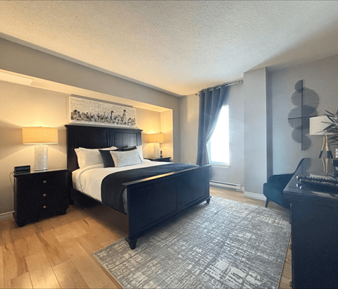 A bedroom with a large bed and a painting above it.