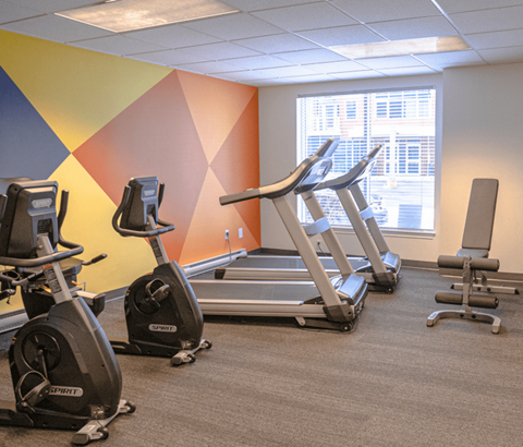 A gym with exercise equipment including treadmills and stationary bikes.