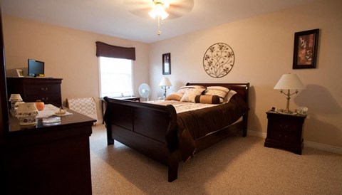 A bedroom with a bed, nightstand, and a fan.