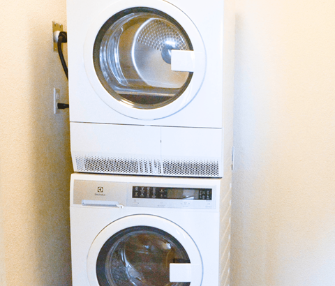 A white washing machine is stacked on top of another white washing machine.