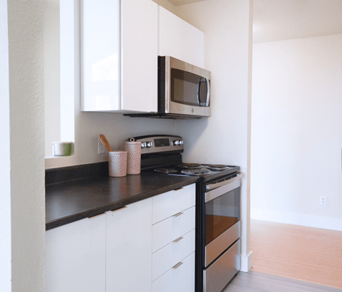 A kitchen with white cabinets and black countertops.