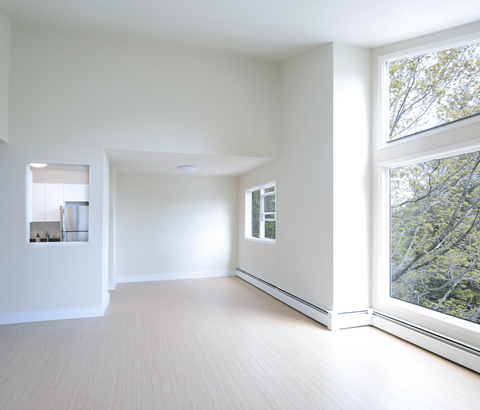 A spacious room with a large window overlooking a tree-filled area.