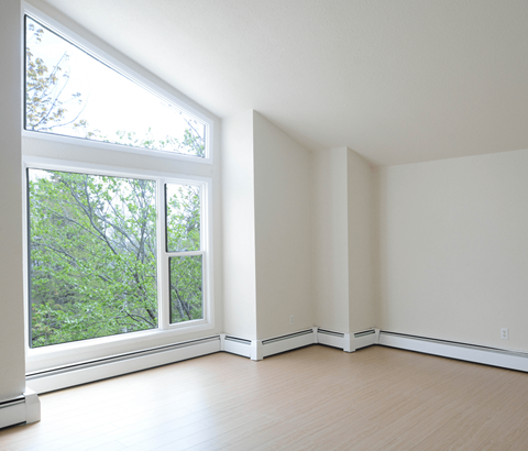 A room with a window overlooking a tree-filled area.
