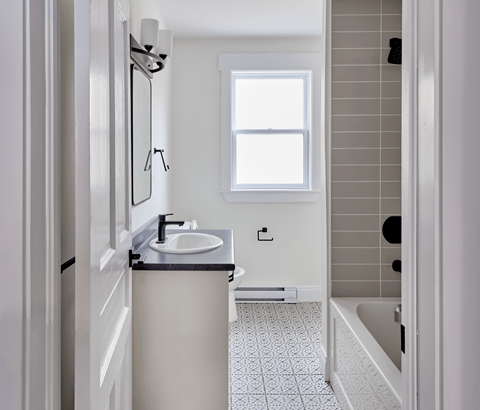 A bathroom with a sink, mirror, and a window.