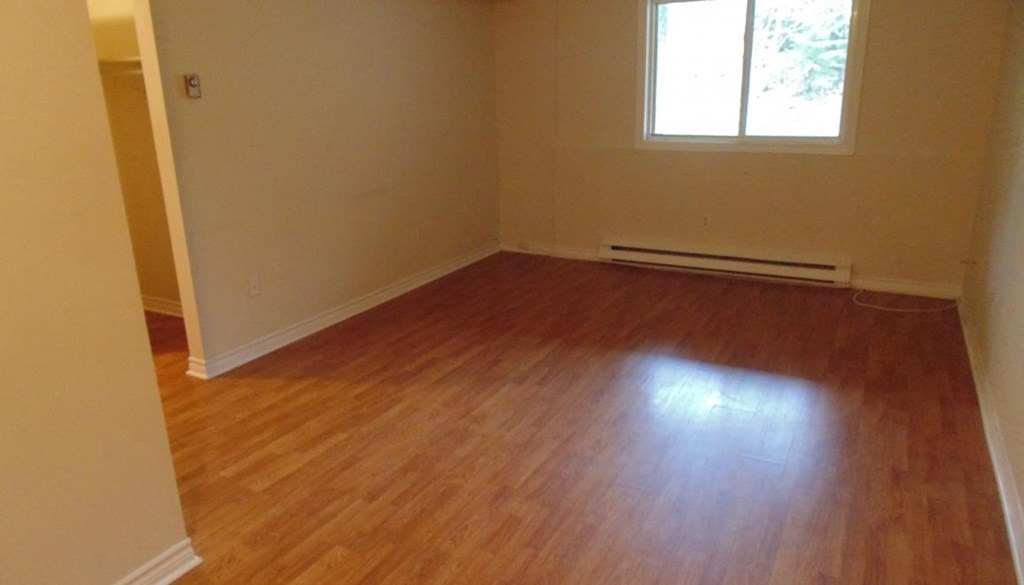 A room with wooden flooring and a window.