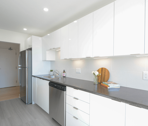 A modern kitchen with white cabinets and a grey countertop.