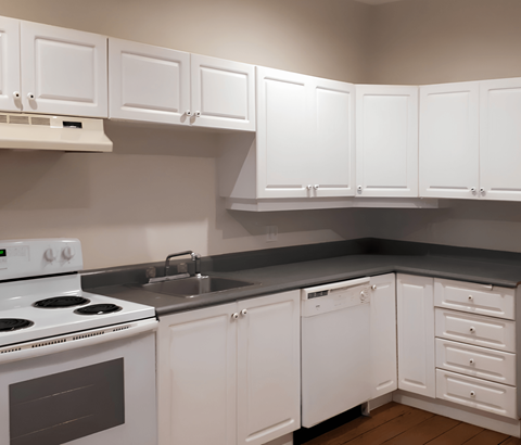 A kitchen with white cabinets and appliances.