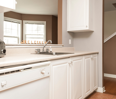 A kitchen with white cabinets and a white sink.