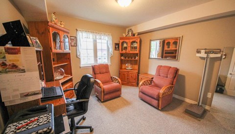 A room with a desk, chairs, and a bookshelf.