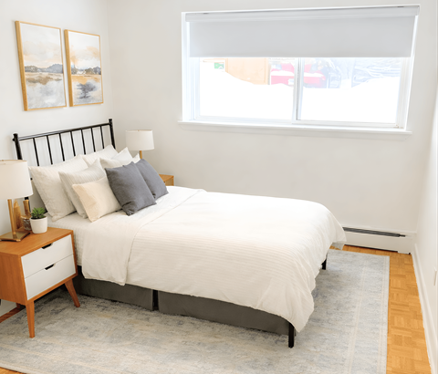 A bedroom with a white bed and a grey rug.