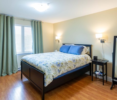 A bedroom with a bed, nightstand, and window.